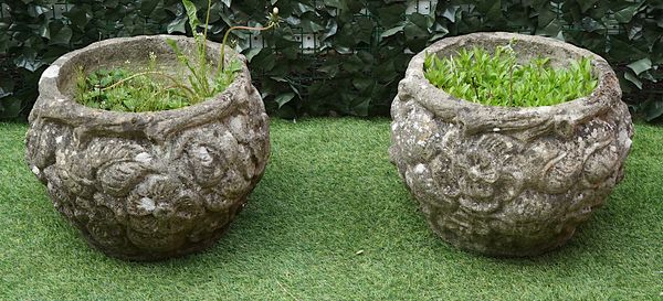 A PAIR OF RECONSTITUTED STONE PLANTERS WITH FLORAL MOULDED GLOBULAR BODIES (2)