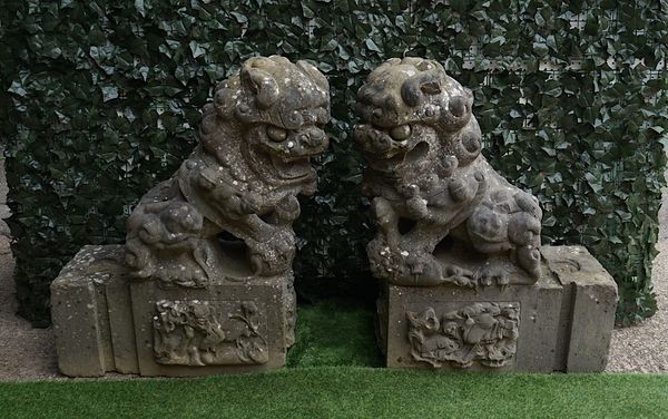 A PAIR OF CARVED GRANITE TEMPLE DOGS ON SQUARE PEDESTALS (2)