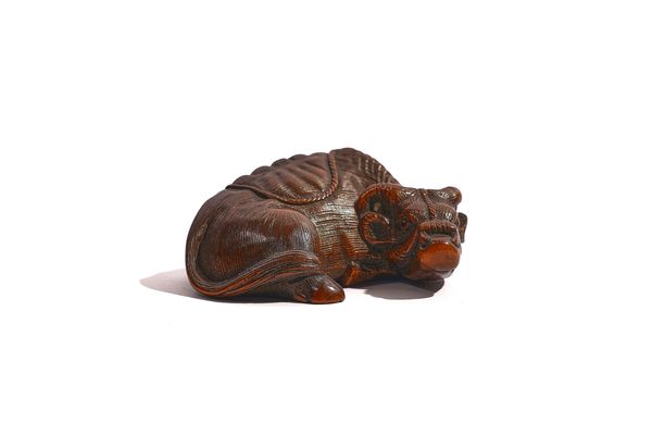 A JAPANESE WOOD NETSUKE OF A RECUMBENT OX