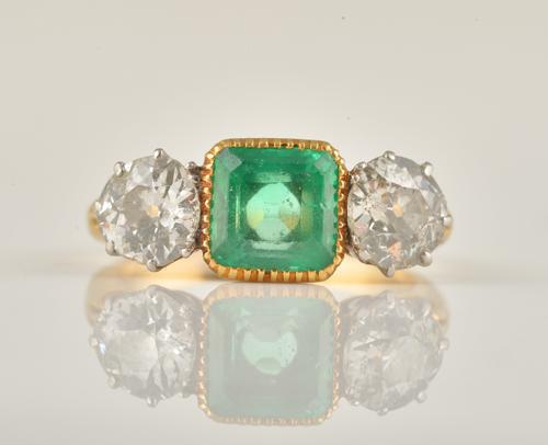 A GOLD, EMERALD AND DIAMOND THREE STONE RING