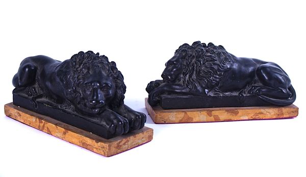 A PAIR OF BRONZE PATINATED COMPOSITION RECLINING LIONS