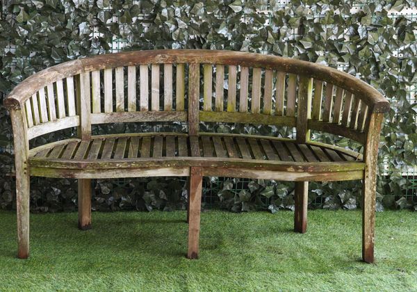 A HARDWOOD SEMI ELLIPTIC GARDEN BENCH OF SLATTED CONSTRUCTION