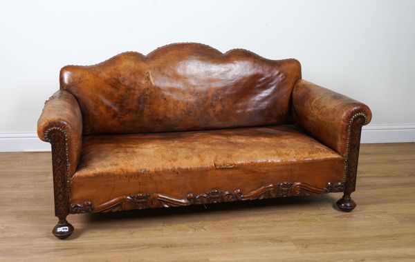 AN EARLY 20TH CENTURY CARVED OAK FRAMED TAN LEATHER UPHOLSTERED HUMP BACK SOFA