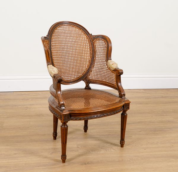 A CHILD’S CARVED MAHOGANY FRAMED CANE BACK ARMCHAIR OF LOUIS XVI DESIGN