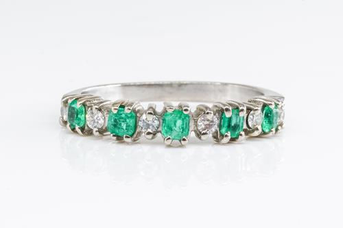 AN EMERALD AND DIAMOND HALF ETERNITY RING