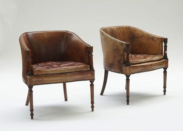 A pair of Regency style brown leather upholstered mahogany framed tub back chairs