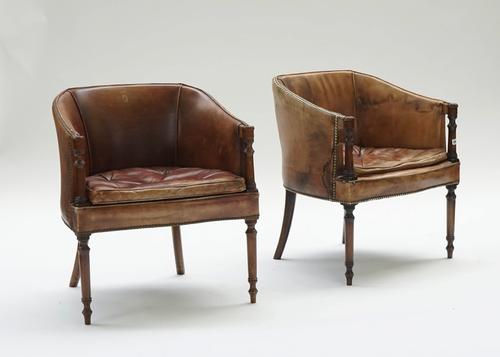 A pair of Regency style brown leather upholstered mahogany framed tub back chairs