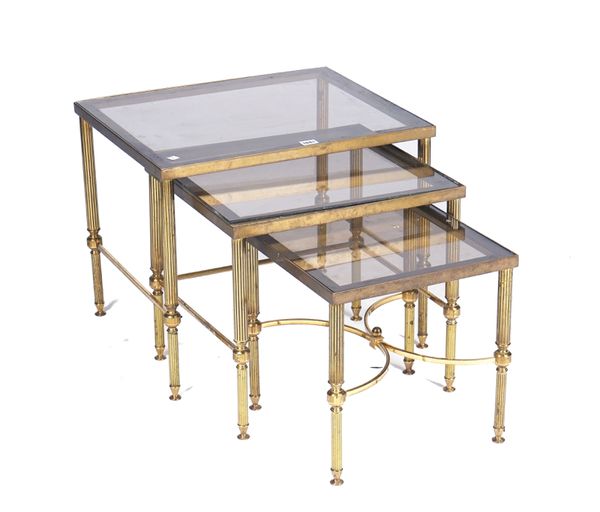 A NEST OF THREE SMOKED GLASS AND LACQUERED BRASS OCCASIONAL TABLES