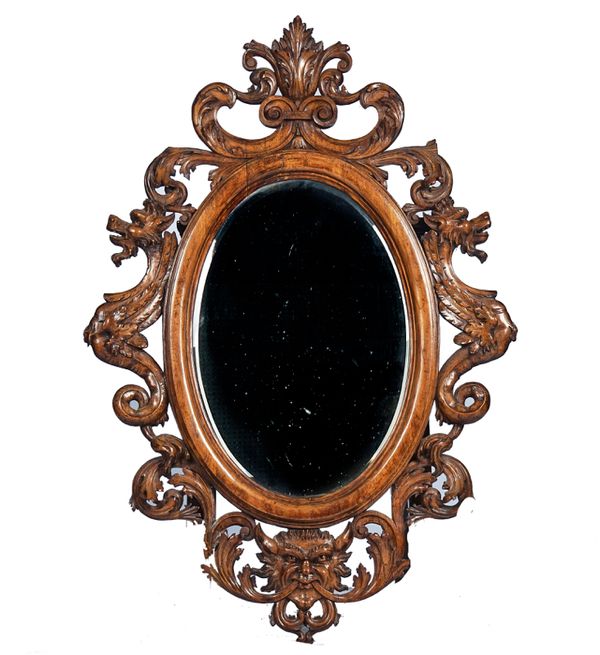 A 19TH CENTURY ITALIAN CARVED WALNUT OVAL MIRROR