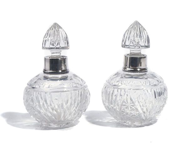 A PAIR OF SILVER MOUNTED FACETED GLASS SCENT BOTTLES AND STOPPERS (2)