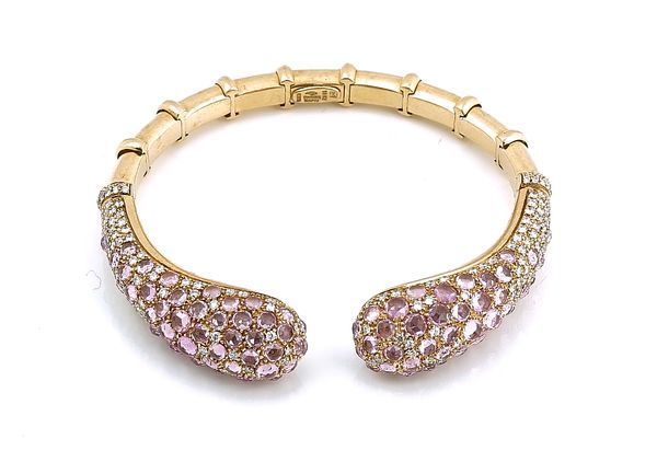 A GOLD, PINK SAPPHIRE AND DIAMOND SET HINGED BANGLE OF TORC DESIGN BY  VIRGINIA CAPRI