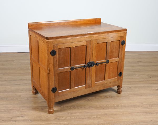 ROBERT MOUSEMAN THOMPSON OF KILBURN; AN ADZE OAK PANELLED TWO DOOR SIDE CABINET ON OCTAGONAL FEET