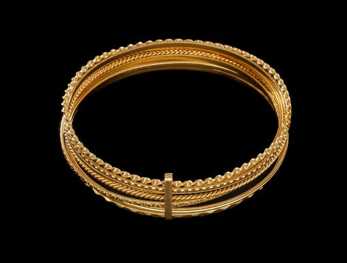 A STACK OF SEVEN GOLD BANGLES
