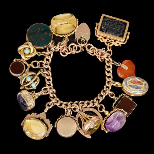 A GOLD CHARM BRACELET FITTED WITH MULTIPLE FOBS AND SEALS