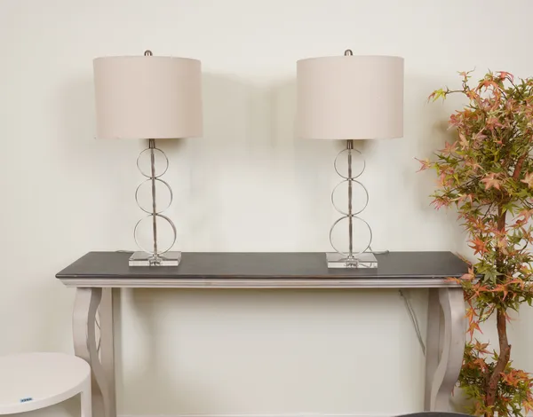 LIGHTING, A PAIR OF CHROME AND GLASS TABLE LAMPS WITH GREY COTTON SHADES