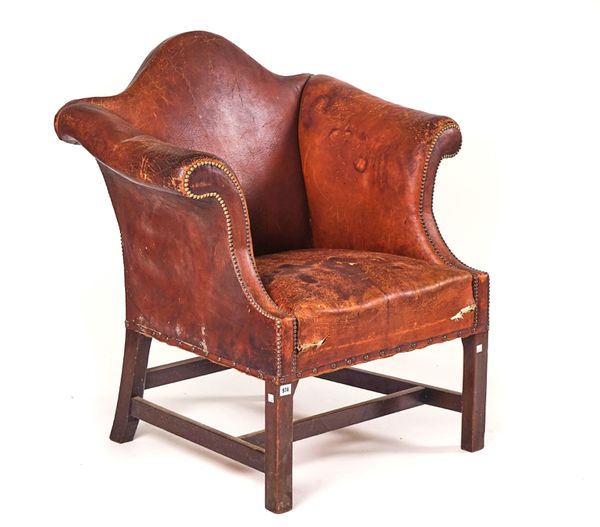 A GEORGE II STYLE TAN LEATHER UPHOLSTERED LOW HUMP BACK ARMCHAIR