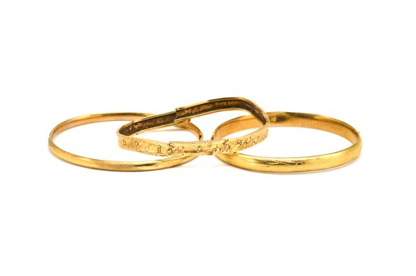 A GOLD OVAL HINGED BANGLE AND TWO FURTHER BANGLES (3)