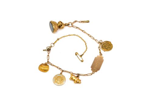 A GOLD IDENTITY BRACELET FITTED WITH FIVE PENDANTS AND CHARMS