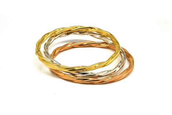 A SET OF THREE 18CT THREE COLOUR GOLD OVAL HINGED BANGLES (3)