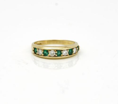 A GOLD, EMERALD AND DIAMOND NINE STONE HALF HOOP RING