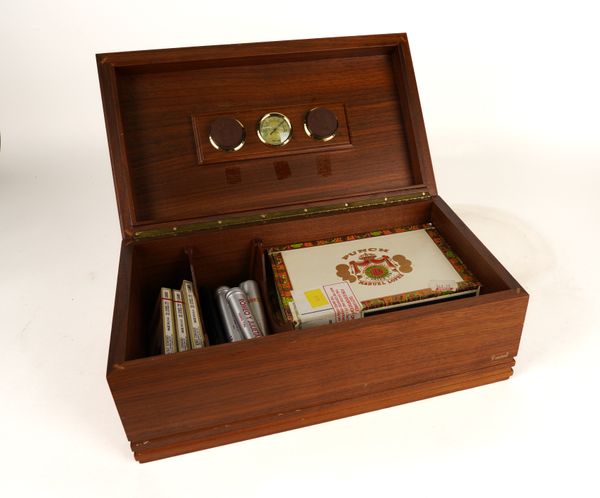 A WALNUT HUMIDOR CONTAINING CIGARS AND CIGAR CUTTERS