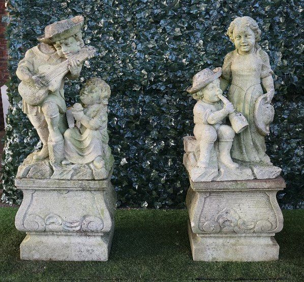 A PAIR OF VINCENZA STONE FIGURE GROUPS OF CHILD MUSICIANS ON SQUARE BALUSTER STANDS