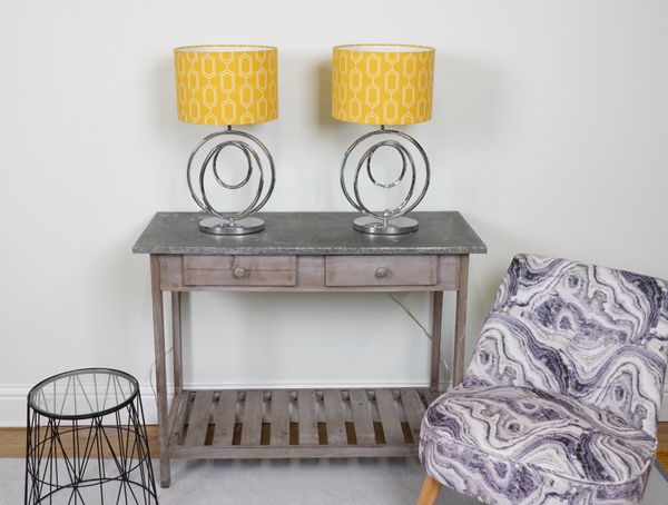 LIGHTING, A PAIR OF CHROME TABLE LAMPS FORMED AS RINGS WITH YELLOW COTTON SHADES