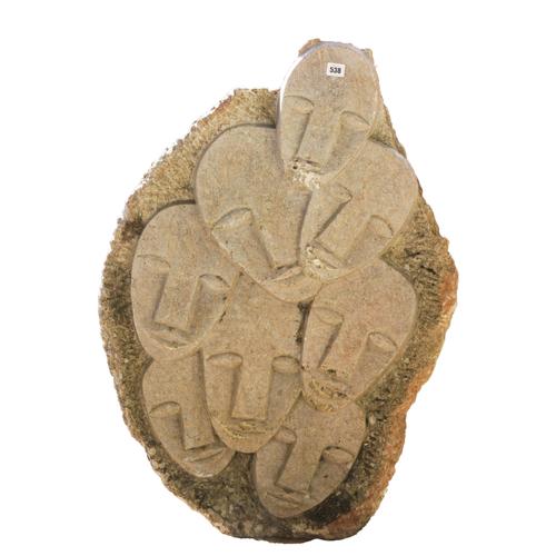 A CARVED AND POLISHED GRANITE STONE SCULPTURE OF RELIEF CARVED MASKS