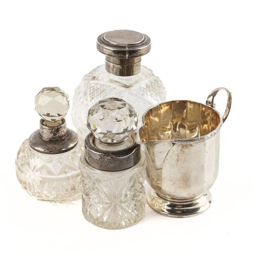 A SILVER MILK JUG AND THREE SILVER TOPPED GLASS BOTTLES (4)