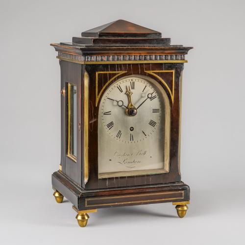 A LATE REGENCY EBONISED AND BRASS LINE-INLAID CHAMFER TOP SMALL MANTEL TIMEPIECE WITH ALARM AND LATER BRACKET