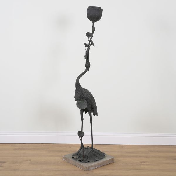 A 20TH CENTURY PATINATED BRONZE FIGURE OF A STANDING CRANE HOLDING LILIES