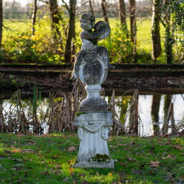 A RECONSTITUTED STONE FIGURE OF A CHERUB MUSICIAN