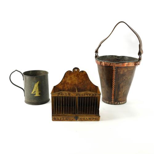 A COPPER AND BRASS MOUNTED LEATHER FIRE BUCKET TOGETHER WITH A TOLEWARE LETTER RACK AND LARGE TANKARD (3)