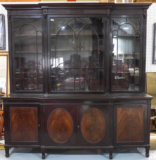 WARING; A GEORGE III STYLE CARVED MAHOGANY BREAKFRONT BOOKCASE