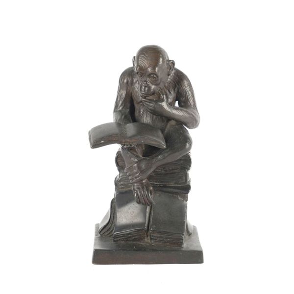 A PATINATED BRONZE FIGURE OF A MONKEY READING