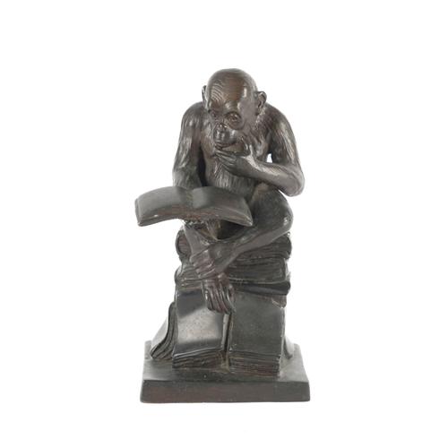 A PATINATED BRONZE FIGURE OF A MONKEY READING