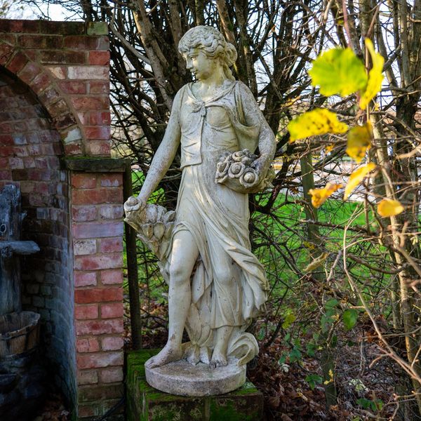 A RECONSTITUTED STONE FIGURE OF A STANDING FLOWER GIRL