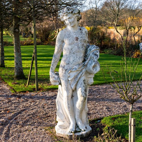 A RECONSTITUTED STONE FIGURE OF A STANDING BACCHUS