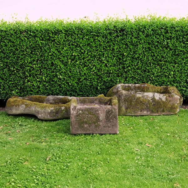 A ROUGHLY HEWN IRREGULAR SHAPED CARVED SANDSTONE TROUGH (3)