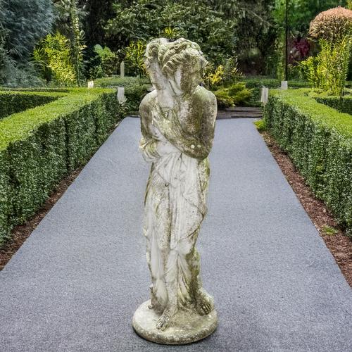 A RECONSTITUTED STONE FIGURE GROUP OF A SCANTILY CLAD GREEK GODDESS