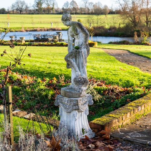 A RECONSTITUTED STONE FIGURE GROUP OF A BATHING LADY