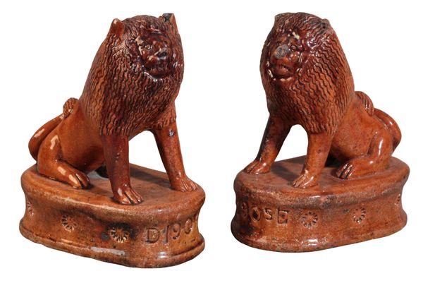 A PAIR OF ENGLISH TREACLE-GLAZED TERRACOTTA LIONS