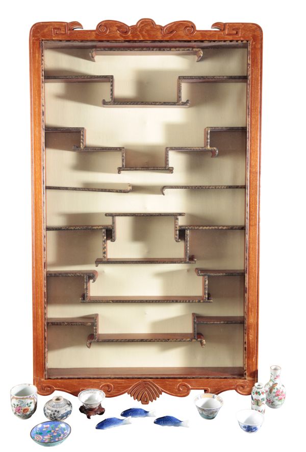 A CHINESE CARVED HARDWOOD WALL MOUNTED CABINET AND CONTENTS