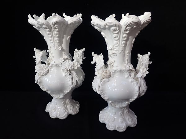 A PAIR OF WHITE GLAZED TWIN HANDLED VASES IN ROCOCO STYLE