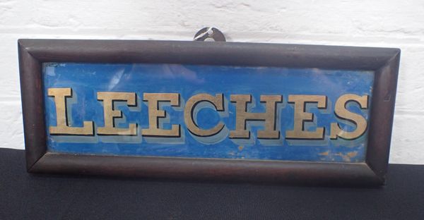 A REVERSE PAINTED AND GILT GLASS 'LEECHES' SIGN