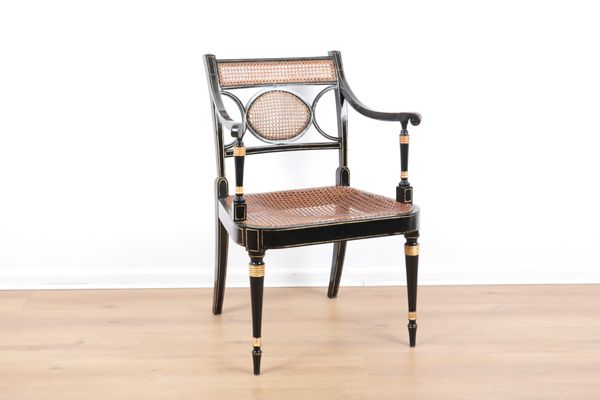 A REGENCY EBONISED AND CANED OCCASIONAL OPEN ARMCHAIR