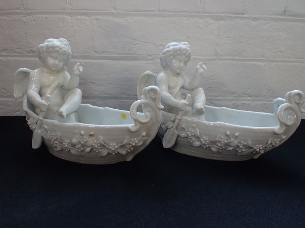 A PAIR OF CONTINENTAL WHITE GLAZED PORCELAIN FIGURES OF PUTTI