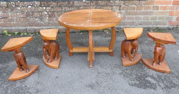 A COFFEE TABLE WITH FOUR CARVED ELEPHANT TABLES