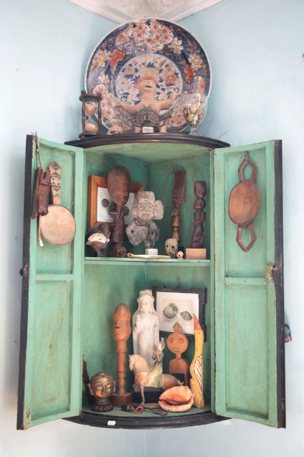 A BLACK LAQUERED BOWFRONT CORNER CABINET AND ETHNOGRAPHIC CURIOSITIES