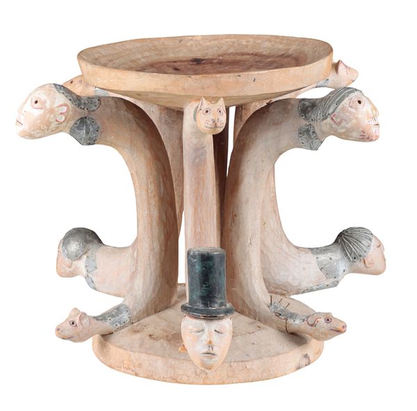 *PETER EUGENE BALL (B.1943) A carved coffee table with human and zoomorphic heads